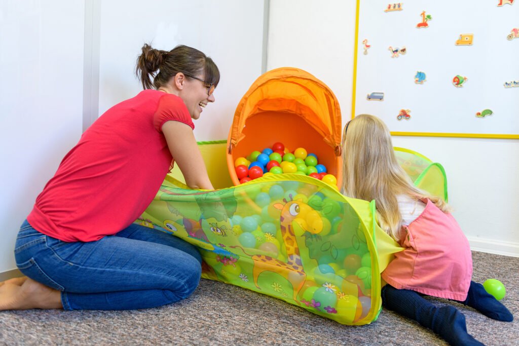 Toddler girl in child occupational therapy session doing playful exercises with her therapist.